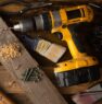 A close-up of various tools including a drill, hammer, and paintbrush on a wooden workbench.